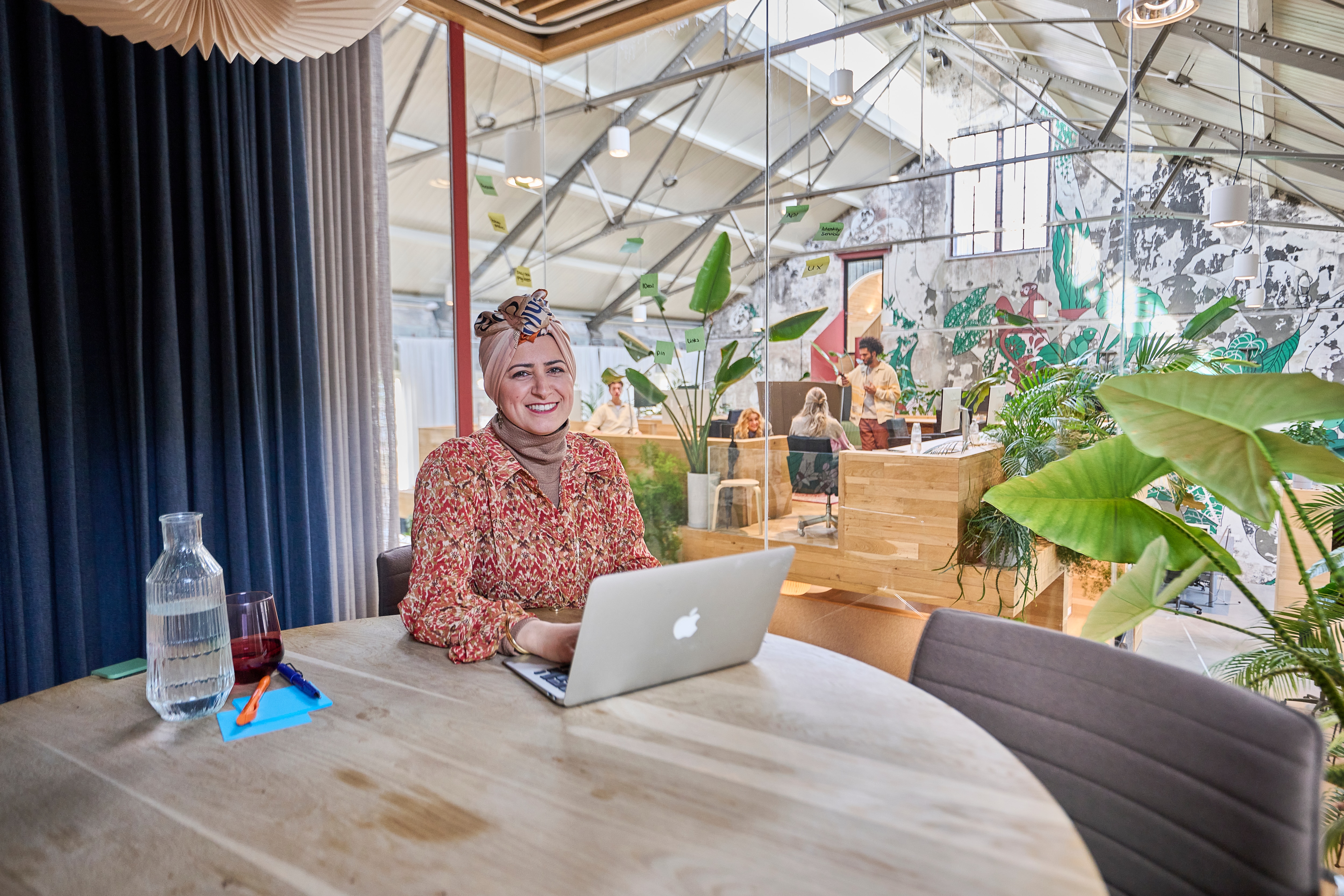 Vrouw zit aan een tafel en werkt op haar laptop in een openbare werkplek op kantoor