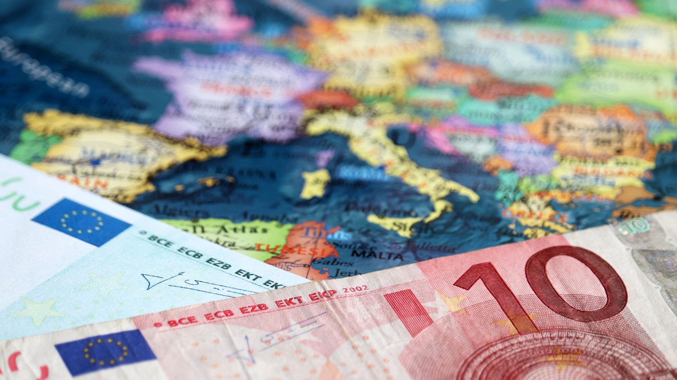 Euro banknotes on the map of Europe, selective focus. Concept for european economy, eurozone countries