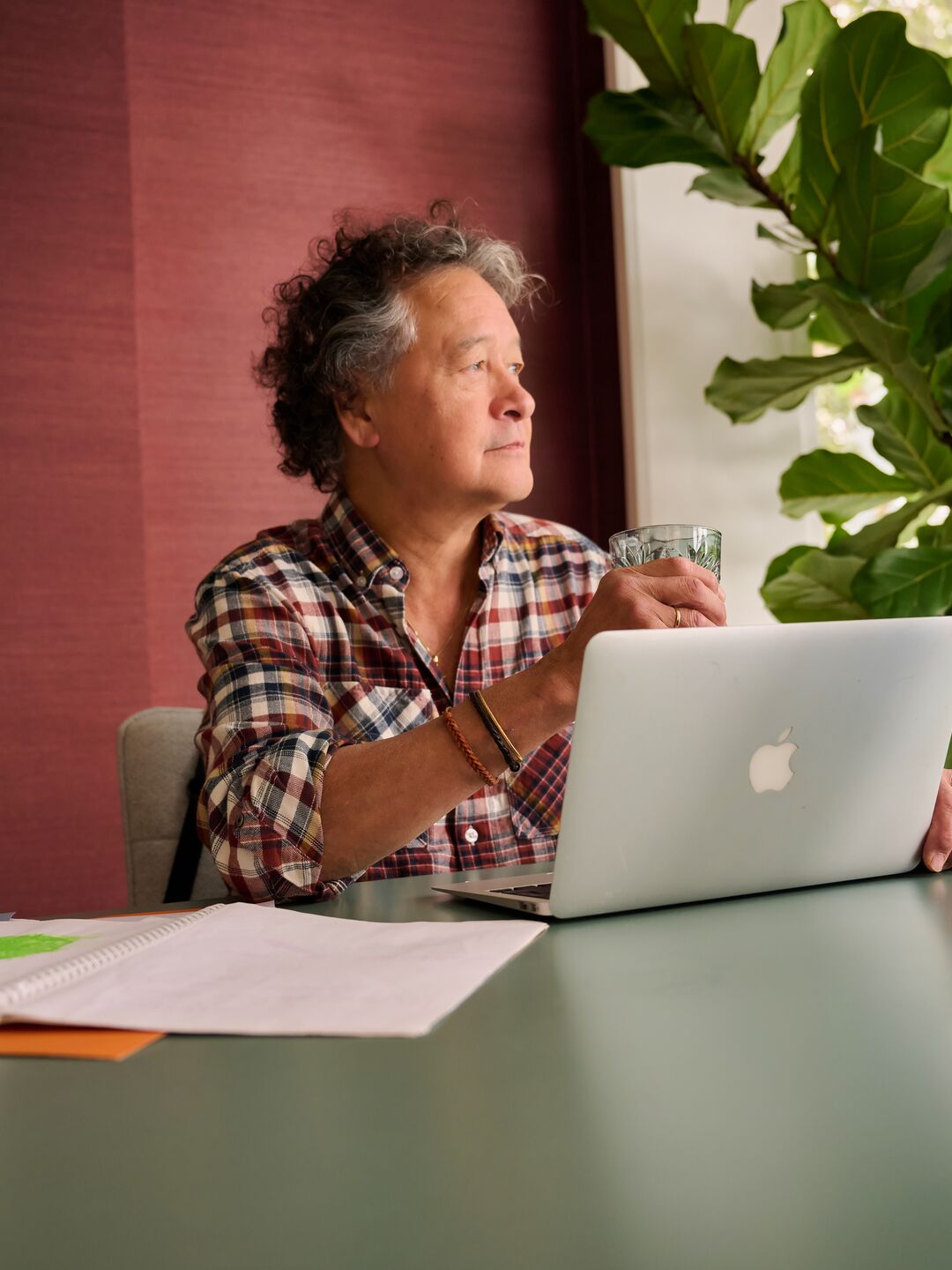Man sitting at the table with her laptop, phone and paperwork. 