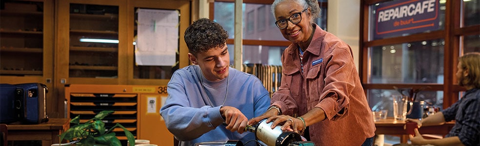 jongen en vrouw sleutelen aan apparatuur in een repaircafe