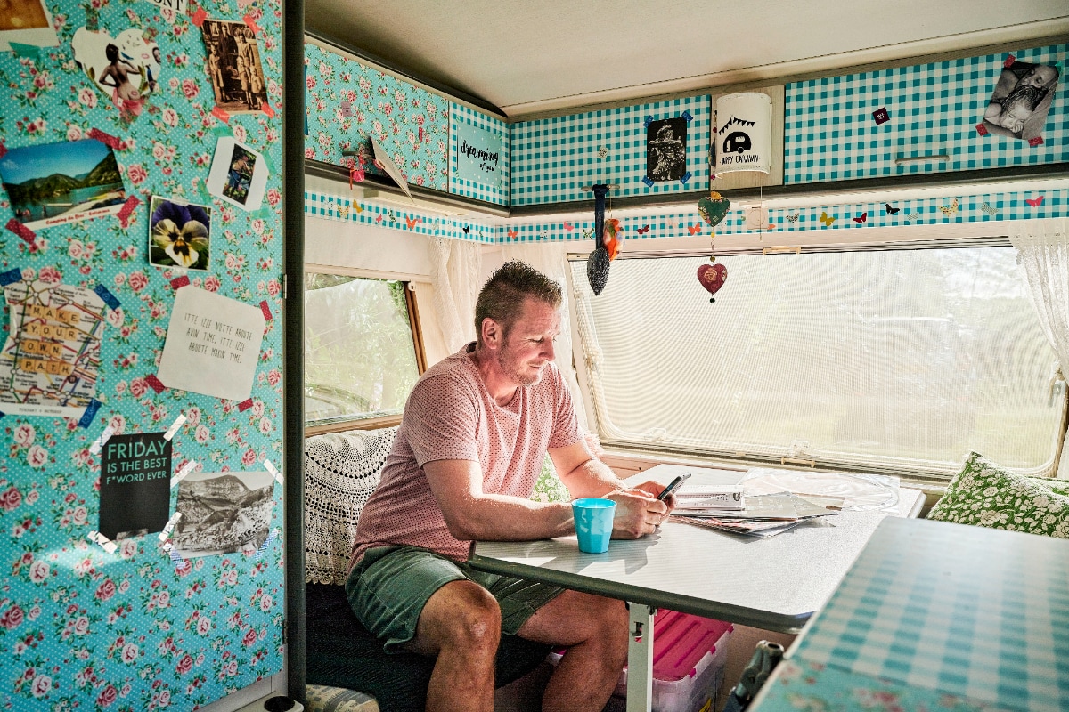 Man kijkt op zijn telefoon in een caravan