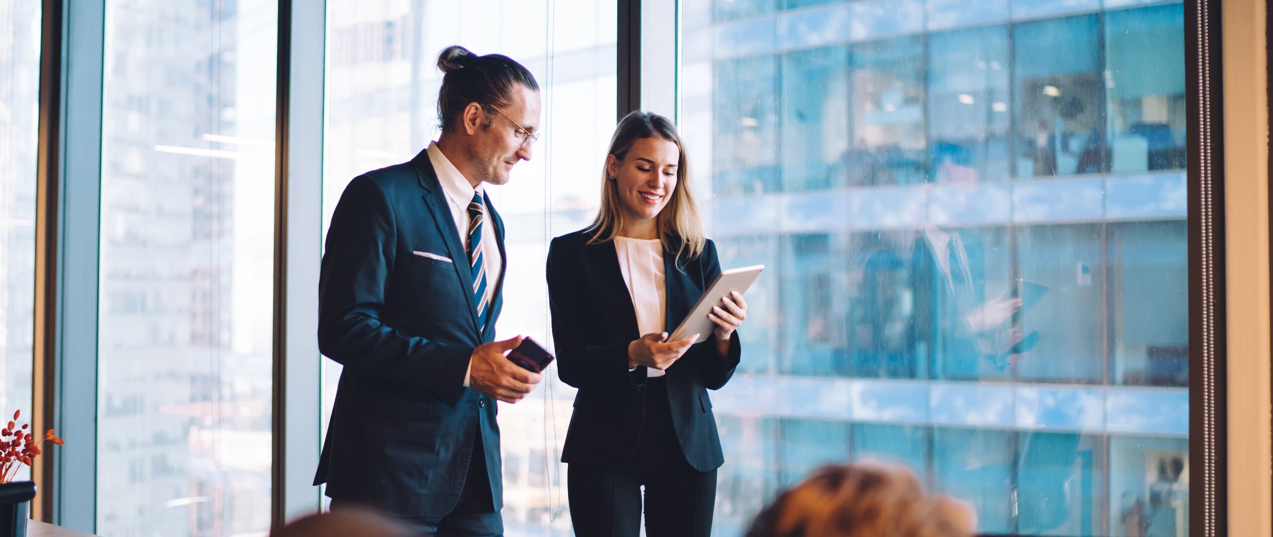 Successful male and female directors in formal wear reading news on web page during break from office cooperation, caucasian partners using company internet connection for communication via touch pad