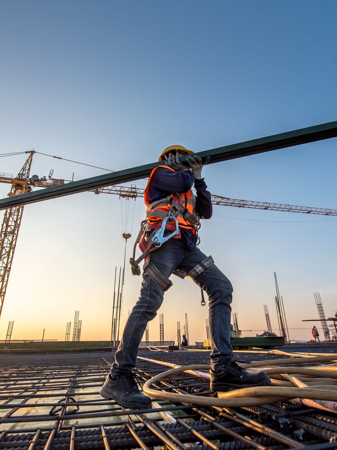 Construction worker walking with beam