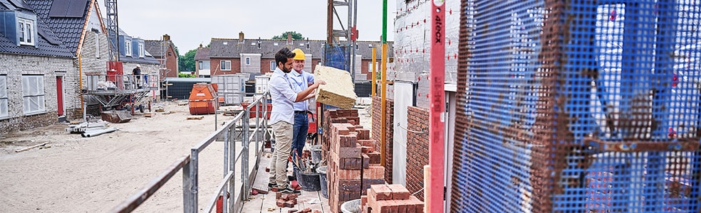 Man en aannemer op een bouwplaats van een nieuwbouwwijk