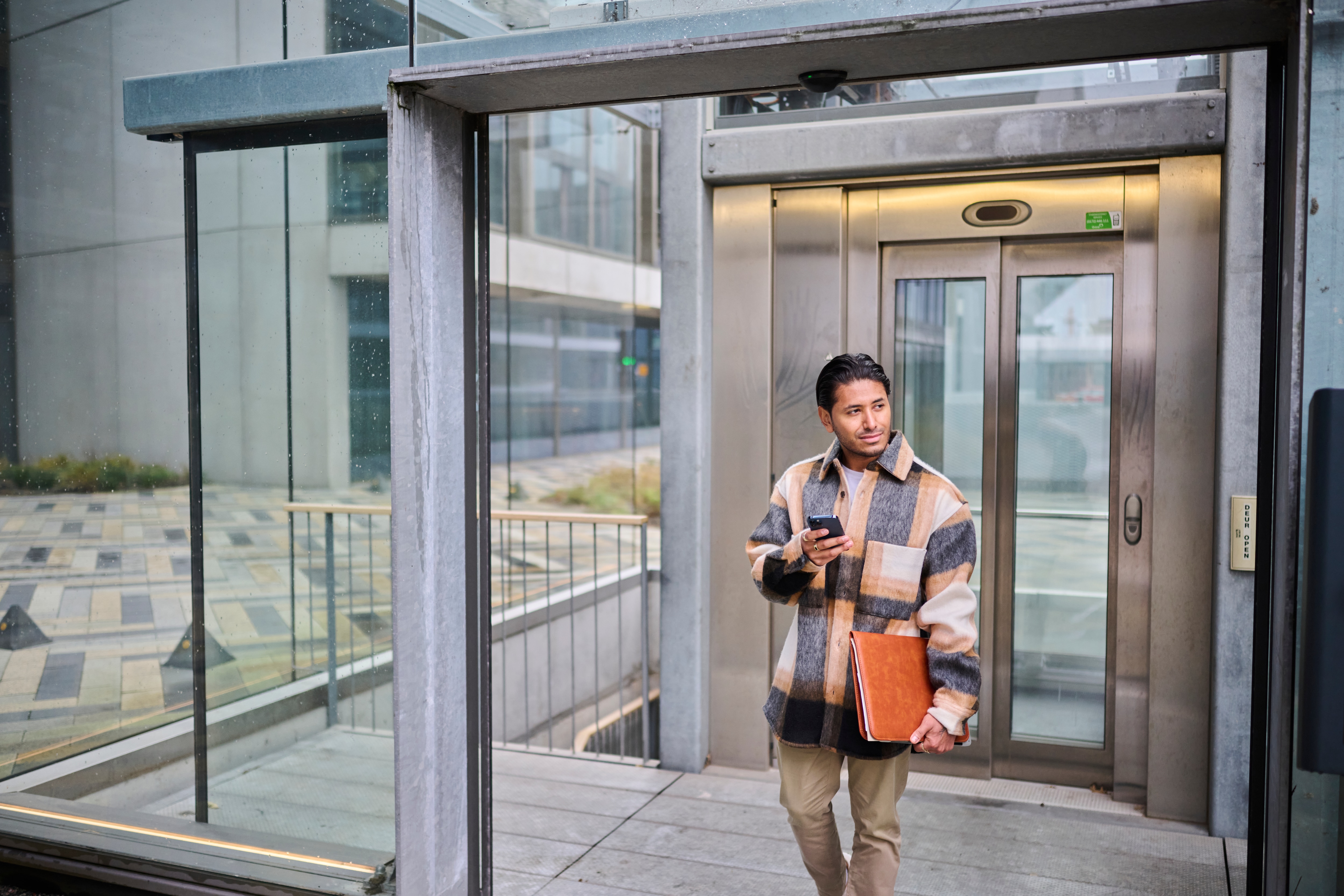 Man bij lift met laptop en telefoon
