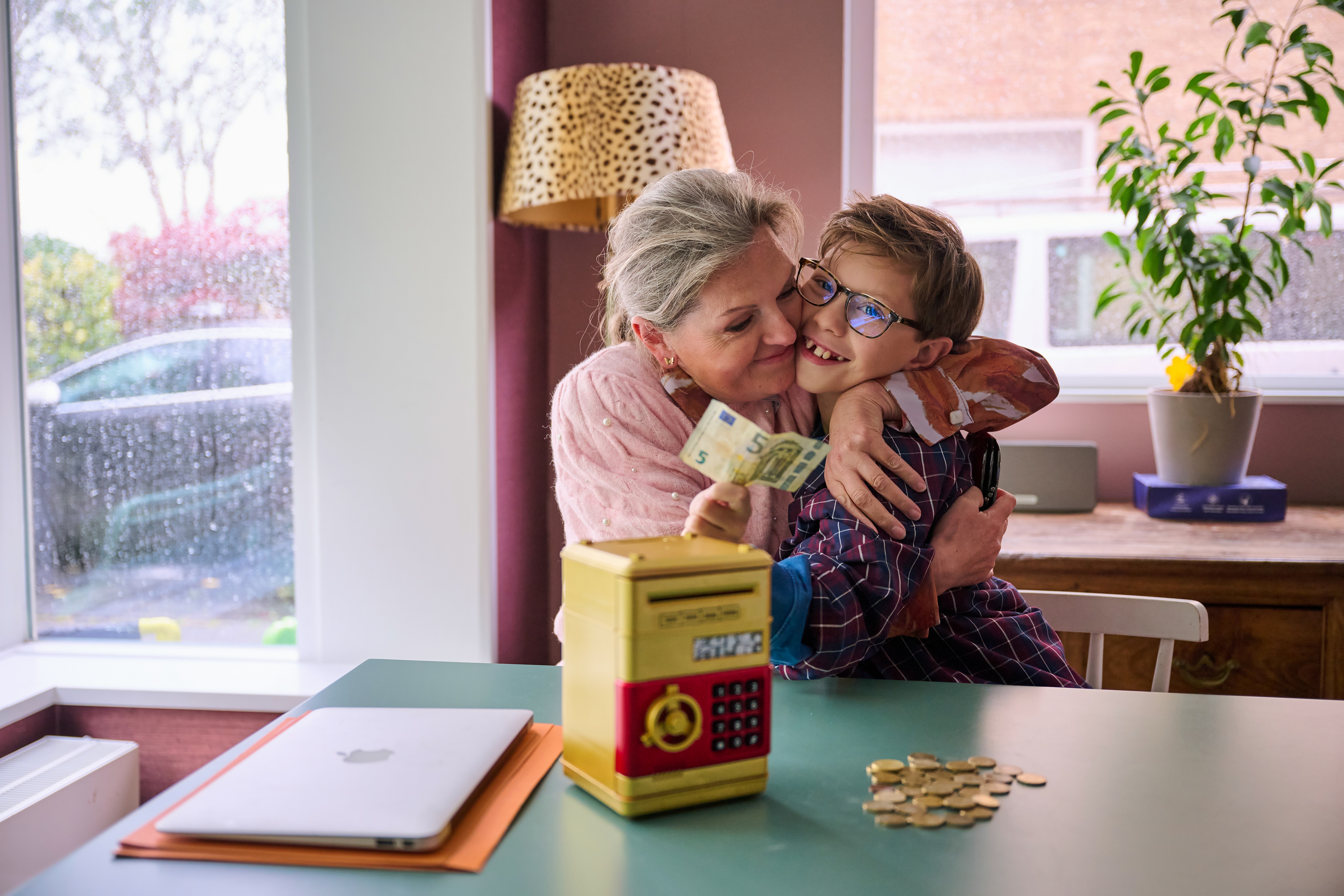 Grandmother teaches grandchild to save with coins in an old piggy bank.