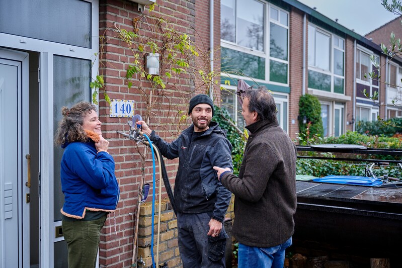 Man aan het werk met kabels voor een huis met twee mensen die er wonen