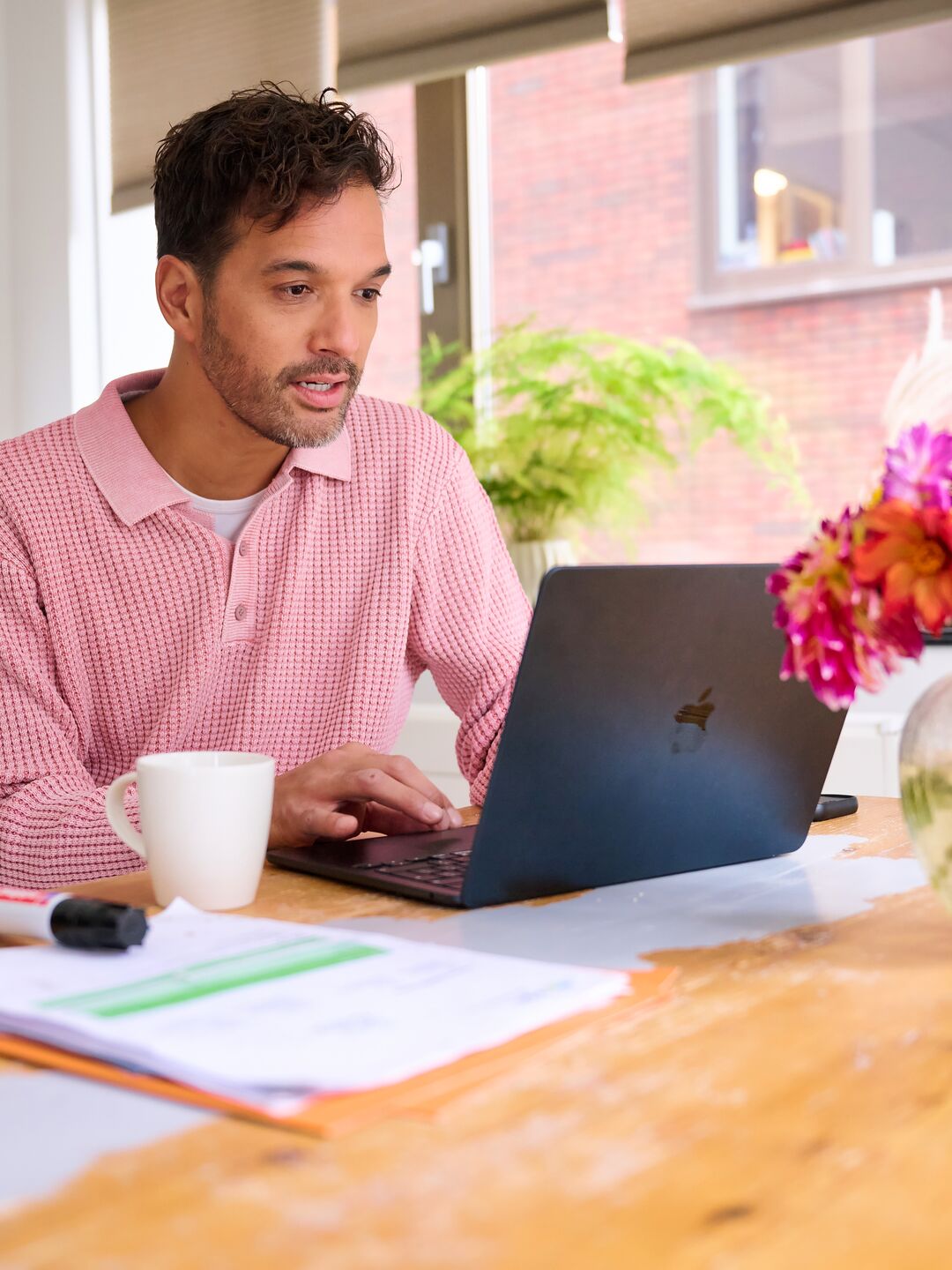 Man sitting at table with laptop and some paper work