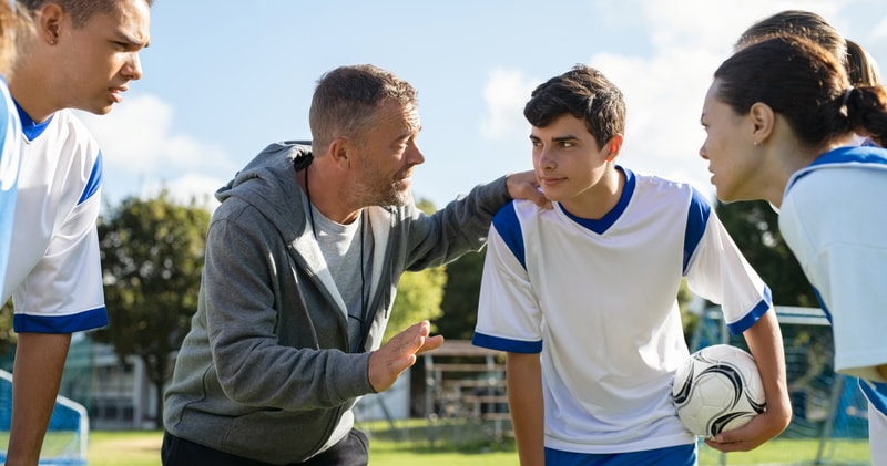 Voetbalcoach praat tegen zijn team op het voetbalveld