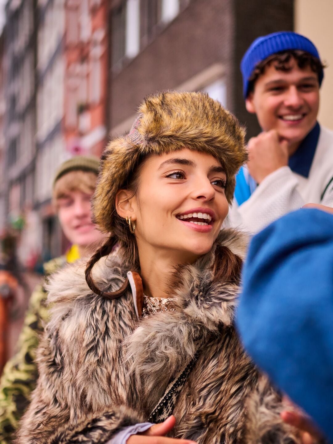 Smiling young woman on the street surrounded by other young adults.