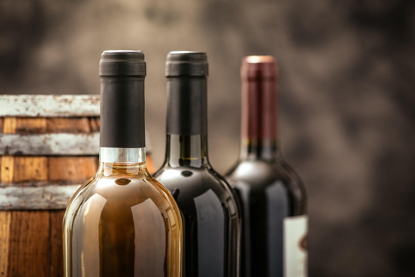 Expensive wine bottles collection and wooden barrel in the cellar, wine tasting and production concept