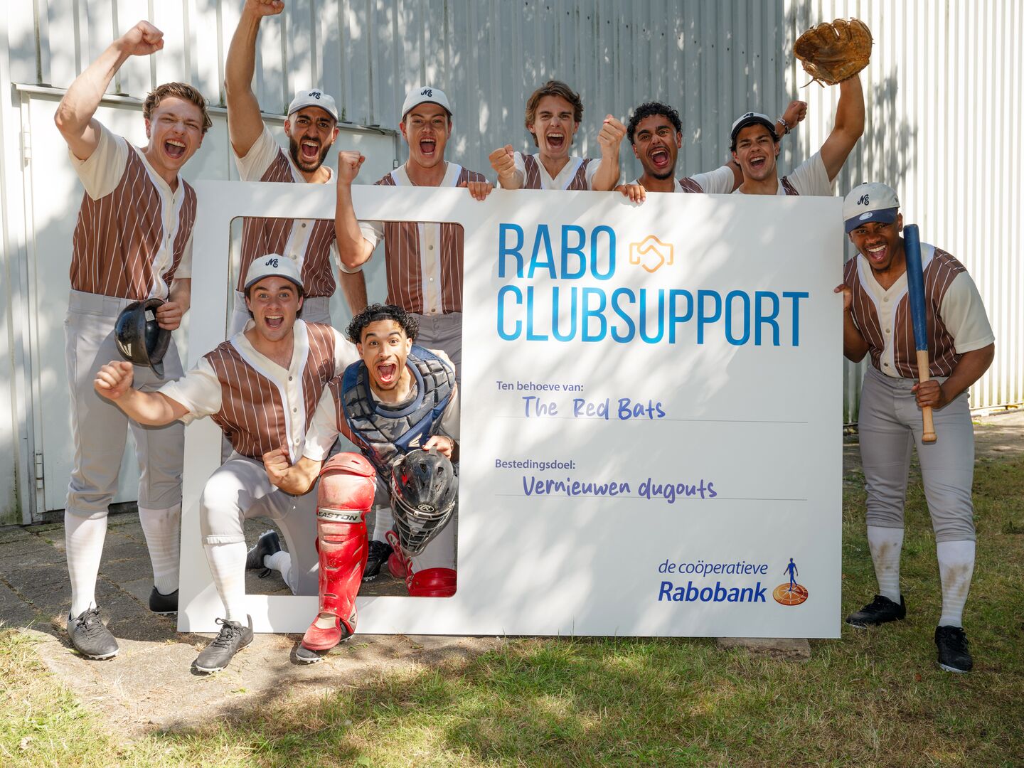 Sports participation. Men's/boys' rugby team with a Rabo ClubSupport cheque. The boys are cheering.