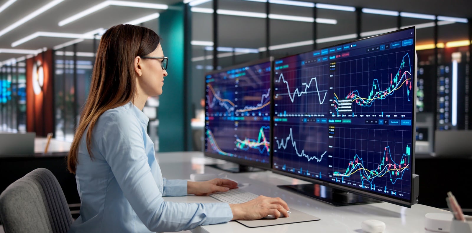 Woman looking at monitors with financial information