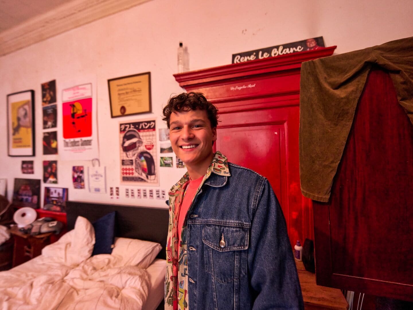A smiling young male student in his dorm room.